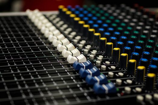 Professional Audio Sound Mixing Console Faders, black desk and white controller Faders with yellow and blue  aux knobs