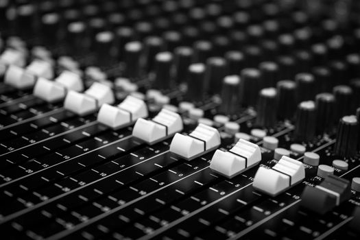 Low level view of Faders on a Professional Audio Sound Mixing Console at music festival, black desk and white Faders