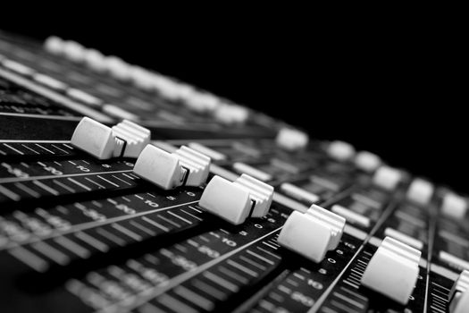 Wide angle closeup of Pro Audio Digital Mixing Console. White Faders and black control Console