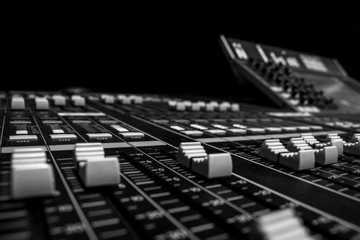 Wide angle closeup of Pro Audio Digital Mixing Console. White Faders and black control Console