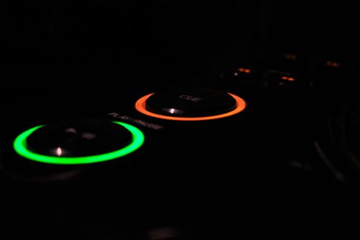 Green play and amber DJ cue trigger buttons on Professional DJ CD USB and SD player, isolated black background