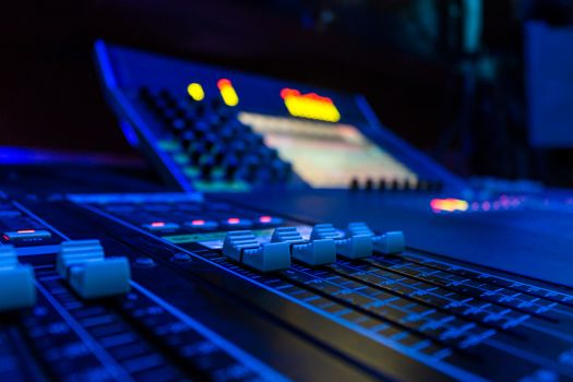 Wide angle closeup of Pro Audio Digital Mixing Console. White Faders and black control Console