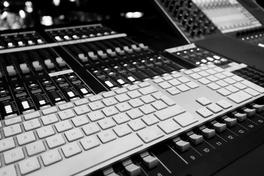 Wide angle closeup of Pro Audio Digital Mixing Console. White Silver and white keyboard and black control Console