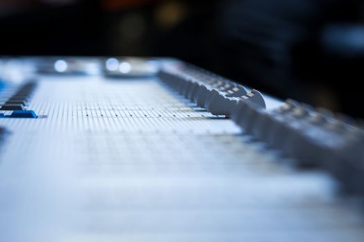 Low level view of a professional audio mixing console with soft focus background