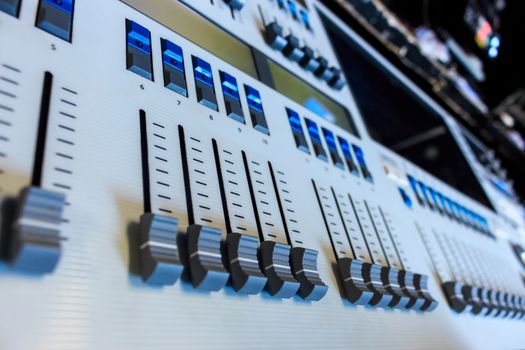 Closeup low view of Professional Lighting Designers Programming Console, blue led buttons on white desk, board