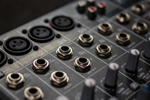 rows of silver gold  audio input connectors, on a professional audio mixing console/ desk