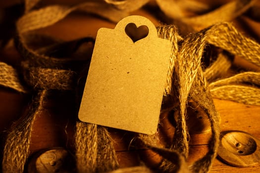 Rectangle Heart Shaped Valentines day gift card tag on wooden background with vintage rustic twine and old buttons