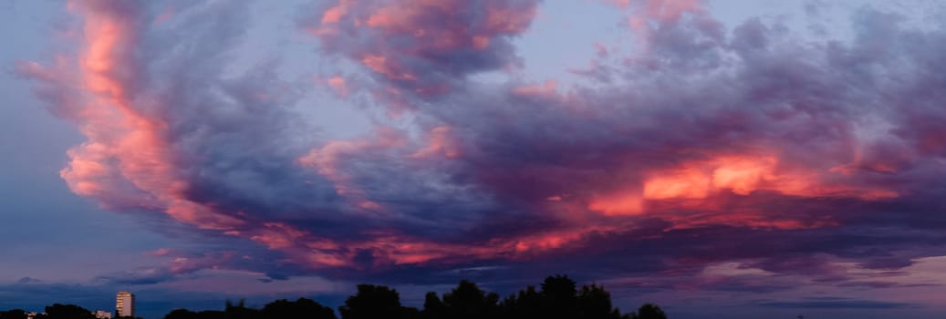 Red clouds over very dark ones form a graceful curve at sunset.