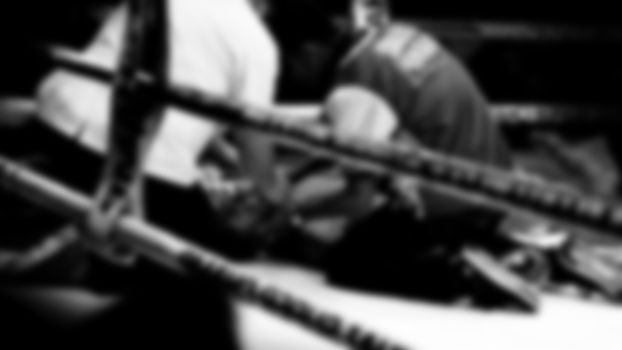 Blurred images black and white photo style of Thai boxing or Muay Thai or Kickboxing which local and foriegn boxer are fighting on the ring at indoor stadium stage as a martial art sport competition for traveller sightseeing