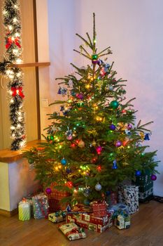 Decorated Christmas tree, and  hidden gifts. Christmas fir tree with colorful lights, decorations and gifts.