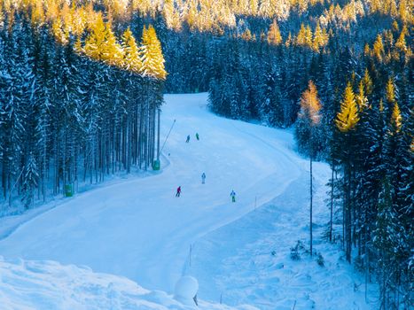 People on ski slope in mountain resort on sunny winter morning.