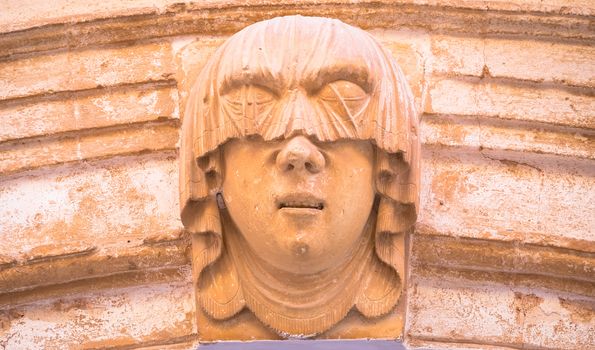 Gothic detail. Young woman portrait at the entrance of a 200 years old building in Ciutadella town, Menorca (Spain)