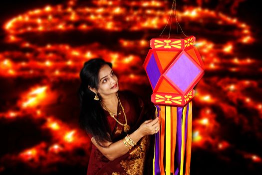 An Indian middleaged woman admiring the traditional lantern in her house, on the eve of Diwali festival in India.
