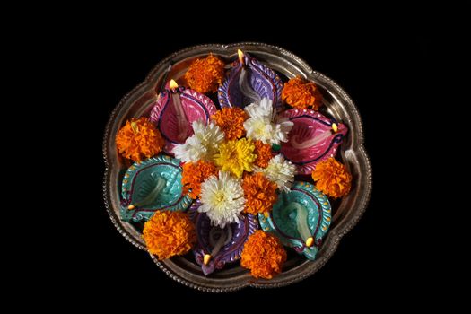 A plate used for traditional hindu rituals with lamps and flowers during Diwali festival in India.