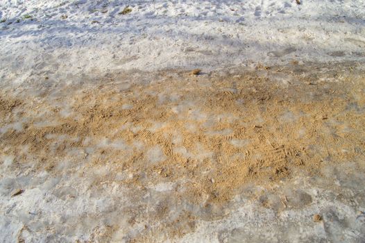 Anti-icing agent and sand on the footpath covered with ice.