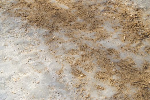 Anti-icing agent and sand on the footpath covered with ice.