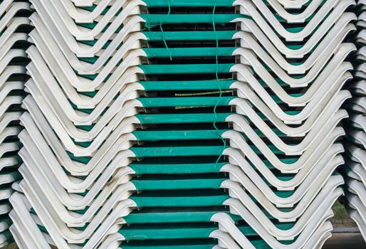 pile of stacked green sunbeds summer season beach lounge background pattern
