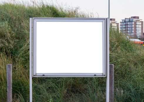 empty and blank metallic information board to put what ever you want with a green grass hill in the background