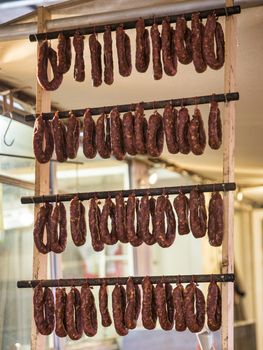 rows of sausages hanging  and drying in the shop , ready for sale