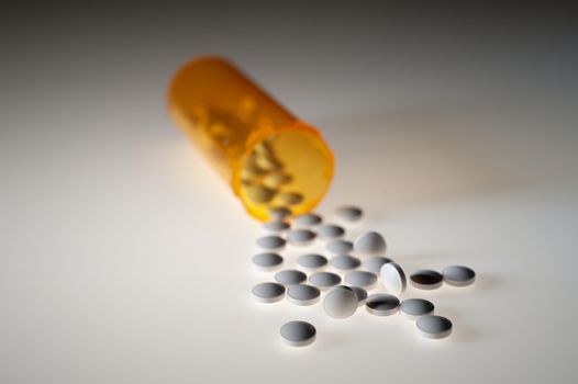 Pills or capsules of medication pouring out of an orange plastic bottle