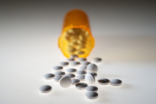 Pills or capsules of medication pouring out of an orange plastic bottle