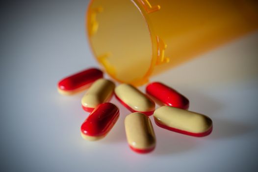 Pills or capsules of medication pouring out of an orange plastic bottle