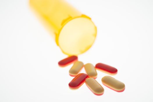 Pills or capsules of medication pouring out of an orange plastic bottle