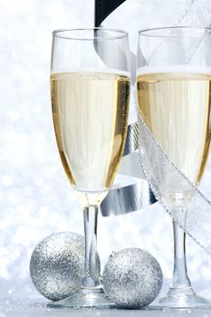 Glasses of champagne and christmas decoration on silver background