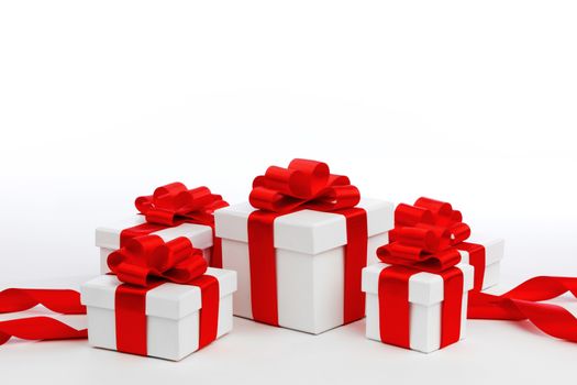 Holiday presents wrapped in white paper with red ribbons, isolated on white
