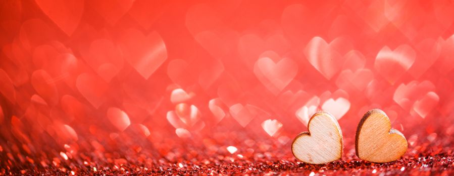 Two wooden hearts on red glowing bokeh hearts background for Valentines day