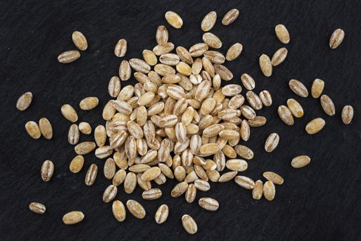 Heap of pearl barley on black background, top view