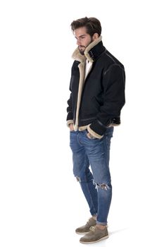 Modern young man in denim and warm jacket standing with hands in pockets isolated on white background in studio