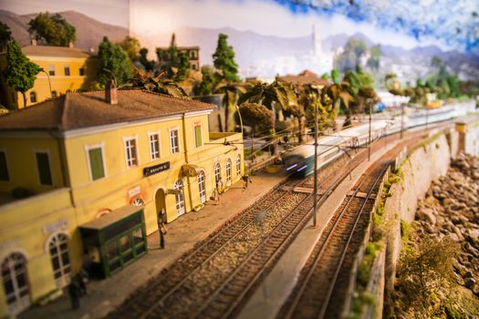 Creative realistic model of railway station with building and passenger and moving train