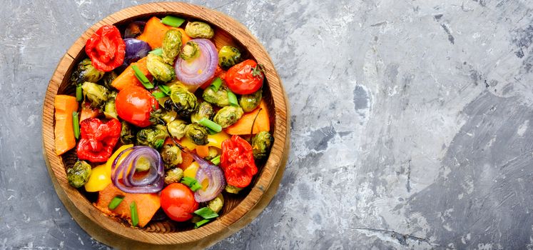 Autumn salad from baked vegetables. Salad from pumpkin, Brussels sprouts, tomatoes and onions