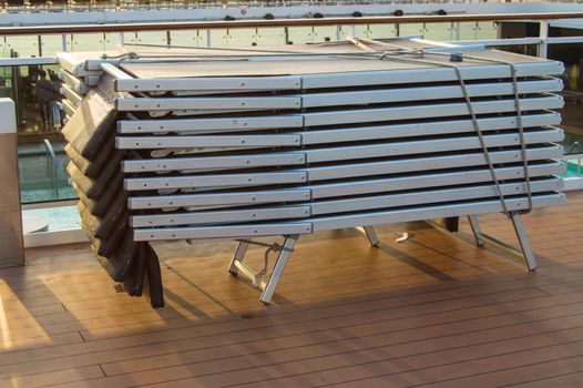 A lot of empty sunbeds, sun loungers are a stack near the pool.