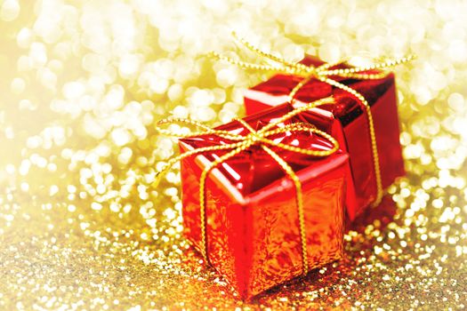 Decorative red boxes with holiday gifts on shiny glitter background