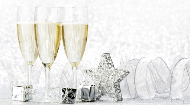 Champagne glasses and christmas decoration on silver bokeh background