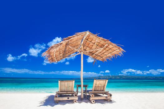 Vacation holidays background - two beach lounge chairs under tent on beach