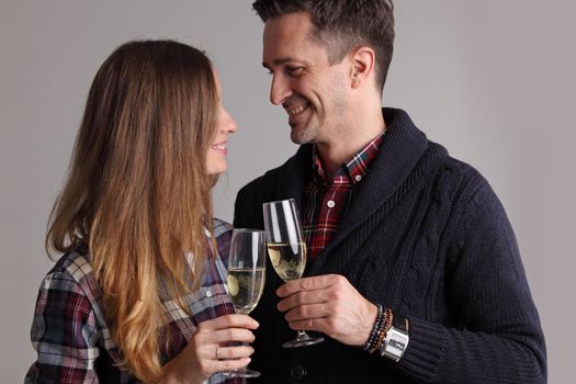 Happy mature couple in casual clothes embracing and clinking glasses of champagne