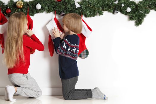 Adorable little children open their stocking gifts on Christmas morning