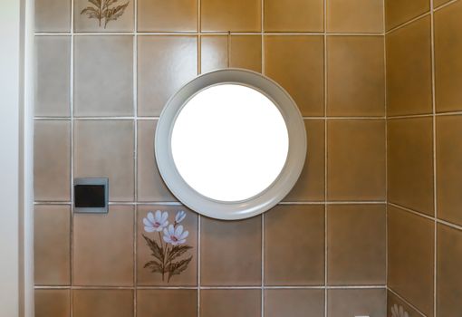 empty blank round mirror frame hanging in the bathroom on a tiled wall decorated with flowers
