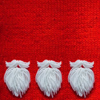 Santa Claus beard on red knitted woolen background with copy space for text Christmas concept