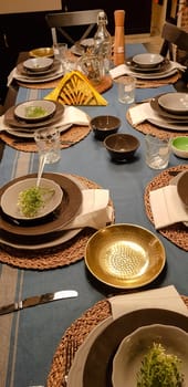 On the festive table in the wedding banquet area there are plates, glasses, candles, cutlery, the table is decorated with compositions in brown