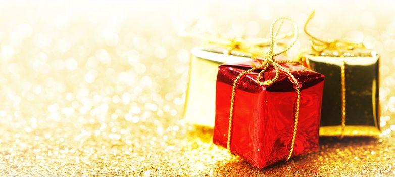 Decorative boxes with holiday gifts on abstract gold background