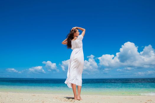 Woman relaxing at the beach enjoying her freedom wear long white dress