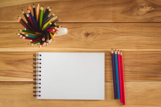 Color pencil and sketchbook on wood table