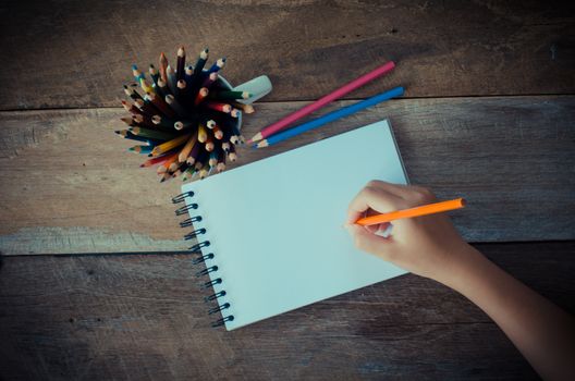 Hand writing in open notebook on table