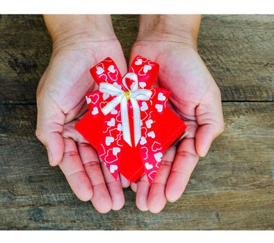 Hands holding gift box on wooden background
