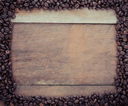 Rectangle frame made of coffee beans on the wooden background