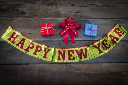 happy New Year message and gift box on wooden background.